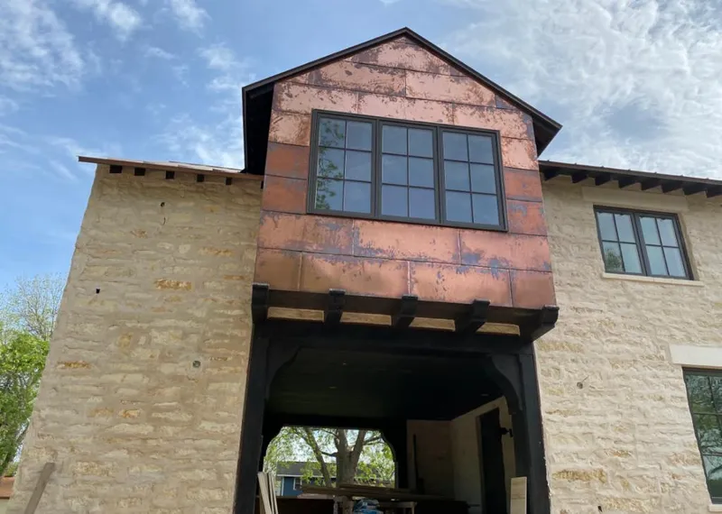 Copper metal panel facade on a stone building for Roof Repair in Forest City