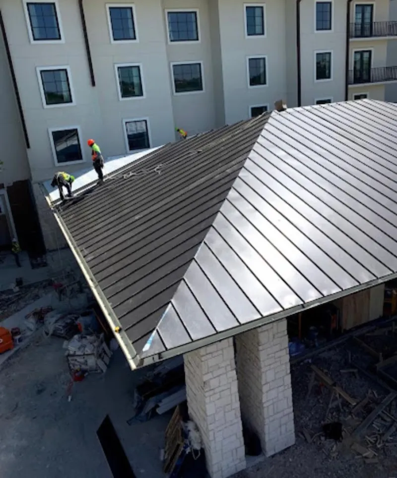 Crew installing standing seam metal roof panels on a commercial project in Forest City